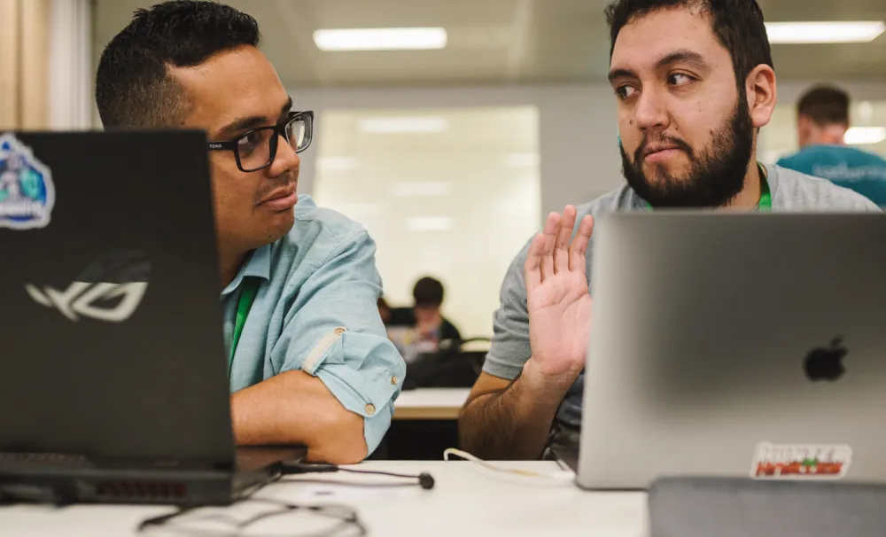 Two hackers talking in front of laptops