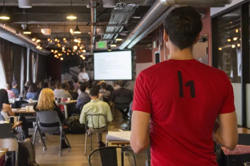 Employee watches a presentation from back of room